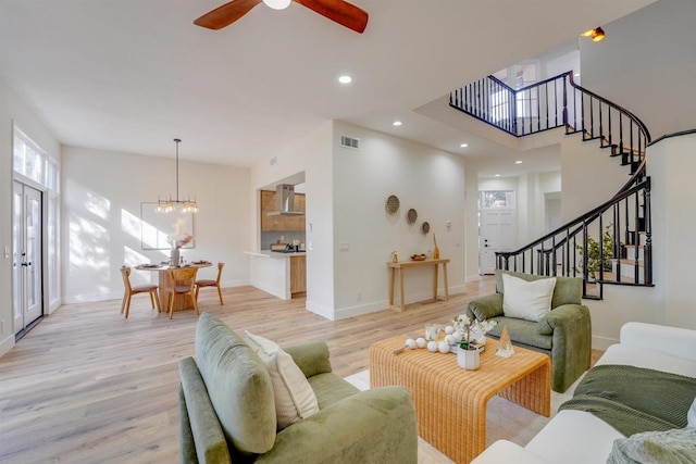 living room featuring a healthy amount of sunlight, ceiling fan with notable chandelier, and light hardwood / wood-style floors