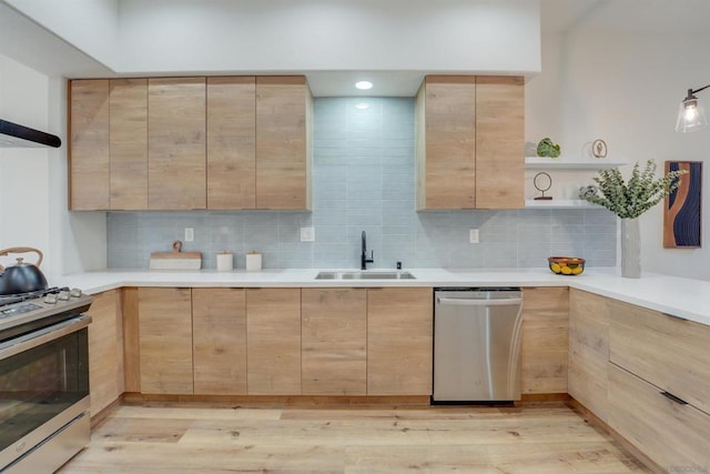 kitchen with stainless steel appliances, sink, light brown cabinets, and light wood-type flooring