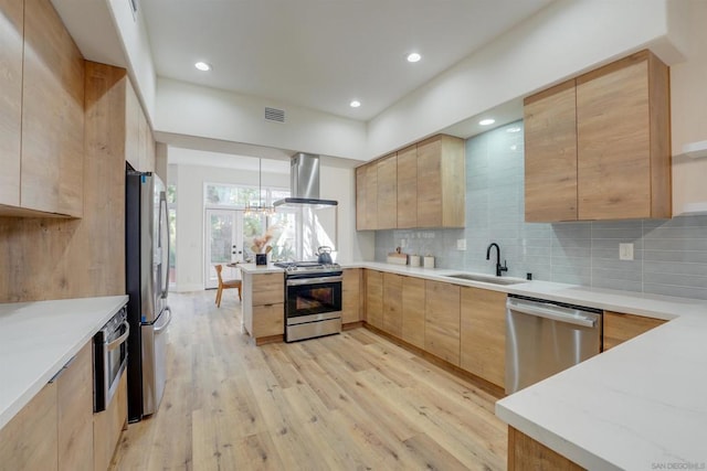 kitchen with appliances with stainless steel finishes, island range hood, light brown cabinetry, decorative light fixtures, and sink