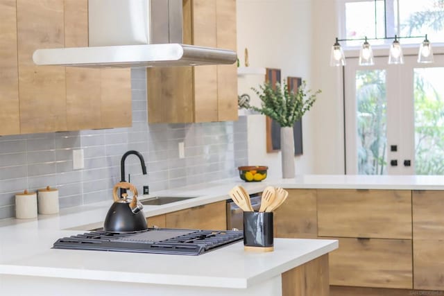 kitchen with tasteful backsplash, stainless steel gas cooktop, sink, and exhaust hood