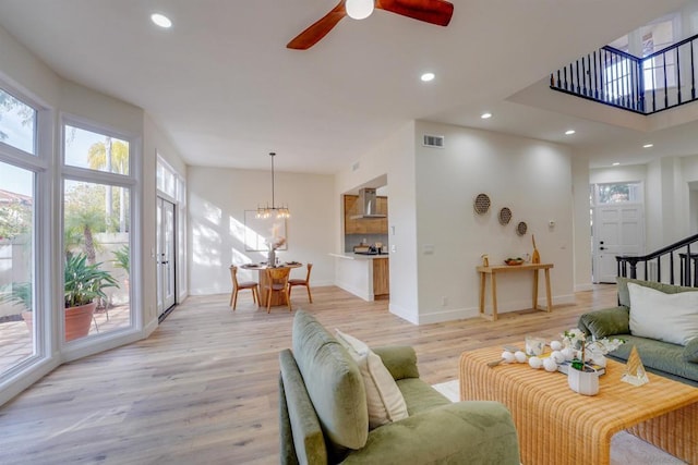 living room featuring ceiling fan with notable chandelier and light hardwood / wood-style flooring