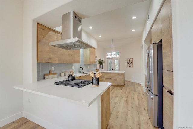 kitchen with appliances with stainless steel finishes, island range hood, decorative backsplash, hanging light fixtures, and kitchen peninsula