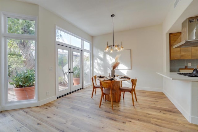 dining space featuring french doors, a chandelier, and light wood-type flooring