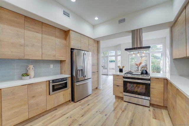 kitchen featuring light brown cabinetry, island exhaust hood, stainless steel appliances, light hardwood / wood-style floors, and backsplash