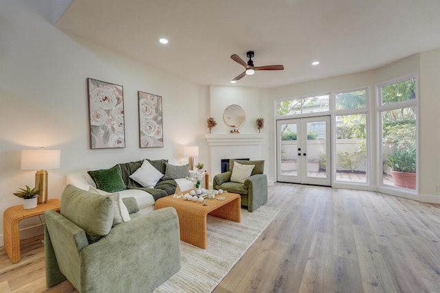 living room with french doors, ceiling fan, and light wood-type flooring