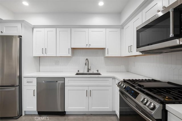 kitchen with sink, backsplash, white cabinets, and appliances with stainless steel finishes