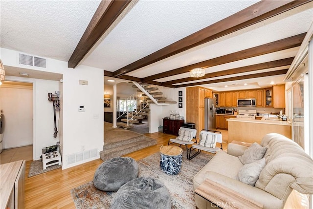 living room with beam ceiling, a textured ceiling, and light hardwood / wood-style flooring