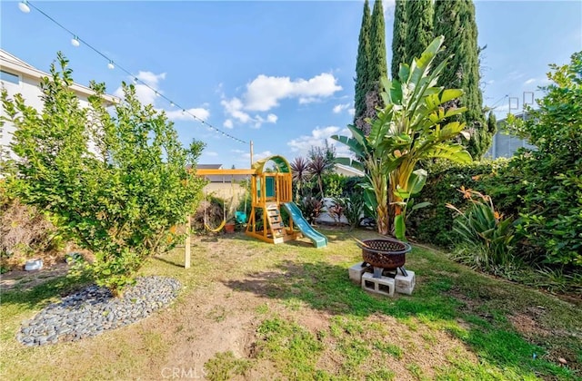 view of playground featuring a fire pit and a lawn