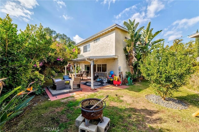 back of property featuring a fire pit, a patio, and a lawn