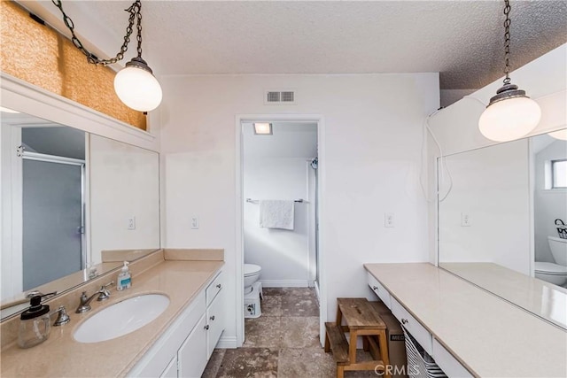 bathroom featuring vanity, a textured ceiling, a shower with door, and toilet