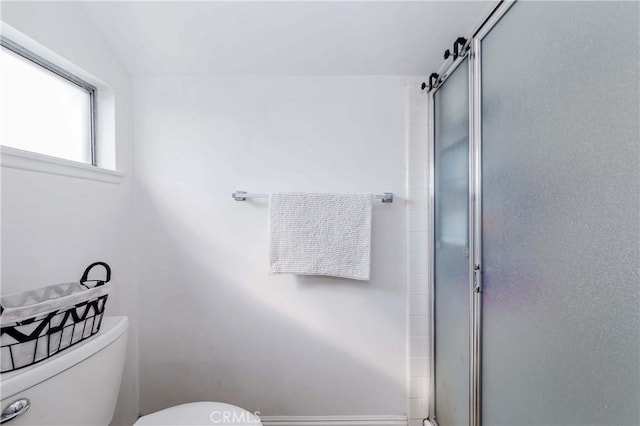 bathroom with a shower with door and toilet