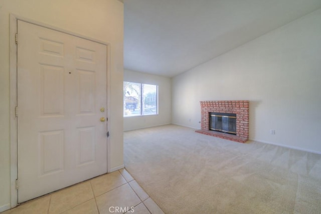 unfurnished living room featuring vaulted ceiling, light colored carpet, and a fireplace