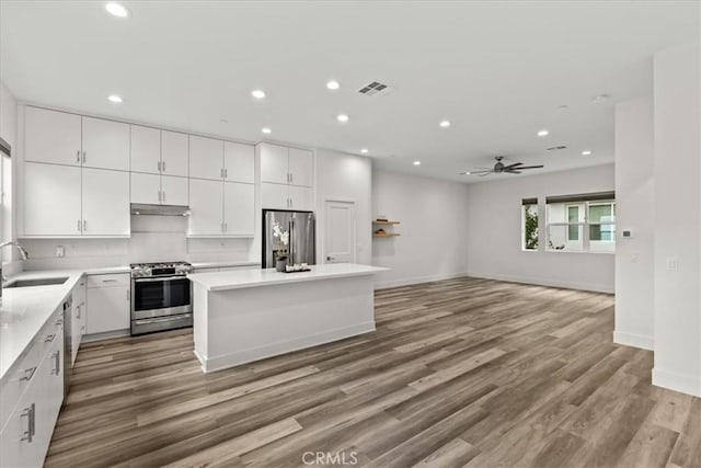 kitchen featuring stainless steel appliances, white cabinetry, a kitchen island, and sink