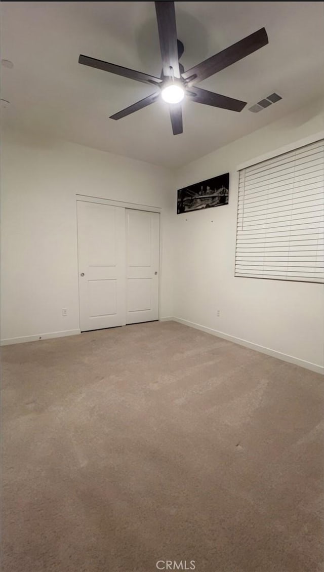 unfurnished bedroom with ceiling fan, light colored carpet, and a closet