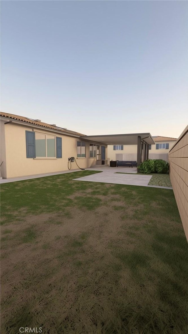 back house at dusk with a yard and a patio