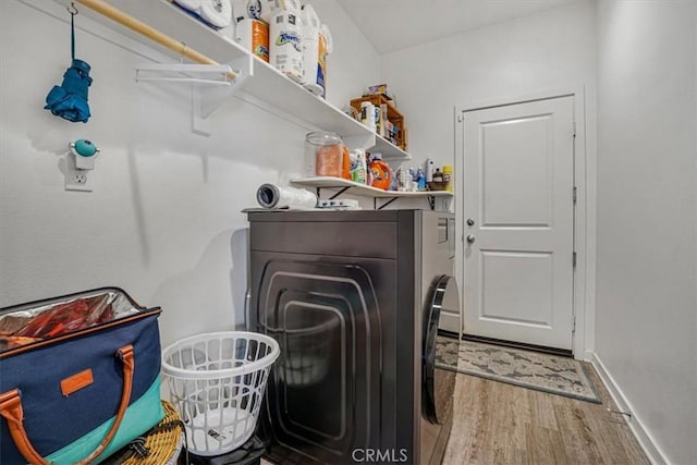 clothes washing area with laundry area, independent washer and dryer, wood finished floors, and baseboards