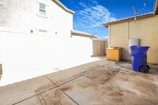 view of property exterior with a patio area, a tiled roof, fence, and stucco siding