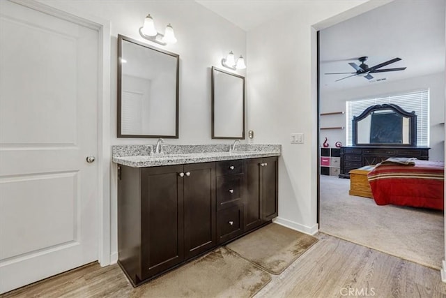 ensuite bathroom with ensuite bathroom, wood finished floors, a sink, a ceiling fan, and double vanity