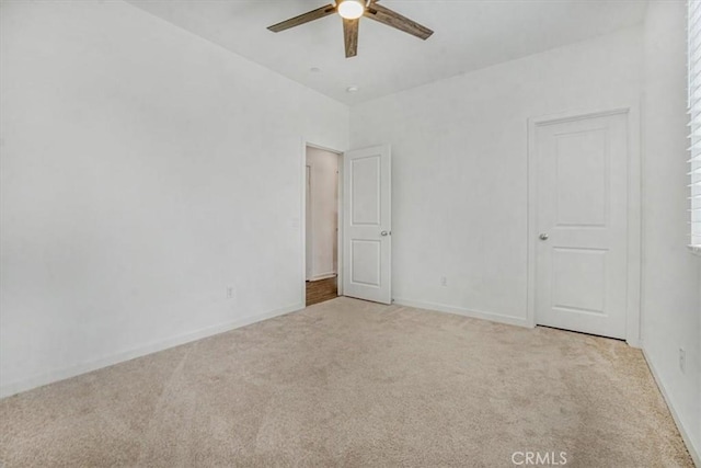 spare room featuring light carpet, ceiling fan, and baseboards