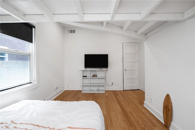 bedroom featuring light hardwood / wood-style flooring and vaulted ceiling with beams