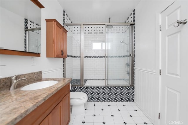 full bathroom with enclosed tub / shower combo, vanity, and toilet