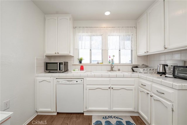 kitchen featuring tasteful backsplash, dishwasher, sink, and white cabinets