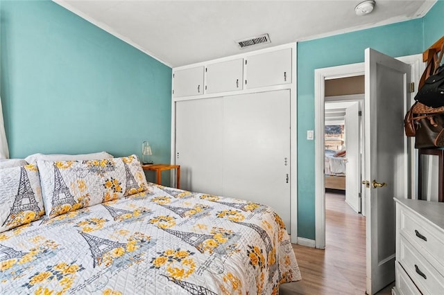 bedroom with crown molding, a closet, and light wood-type flooring