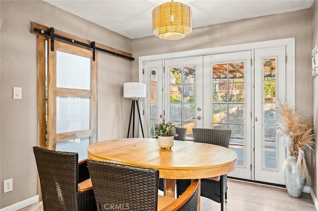 dining space with french doors, a barn door, and light wood-type flooring