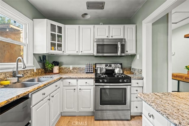 kitchen with white cabinetry, stainless steel appliances, sink, and light wood-type flooring