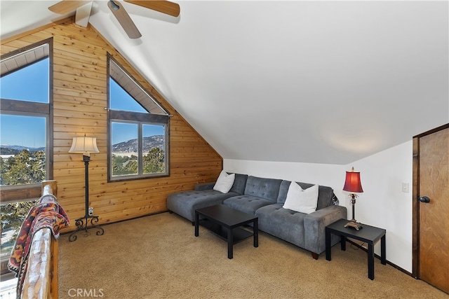 living room with light colored carpet, wooden walls, a mountain view, and vaulted ceiling