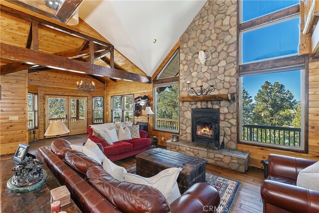 living room featuring hardwood / wood-style flooring, wooden walls, high vaulted ceiling, a fireplace, and beamed ceiling