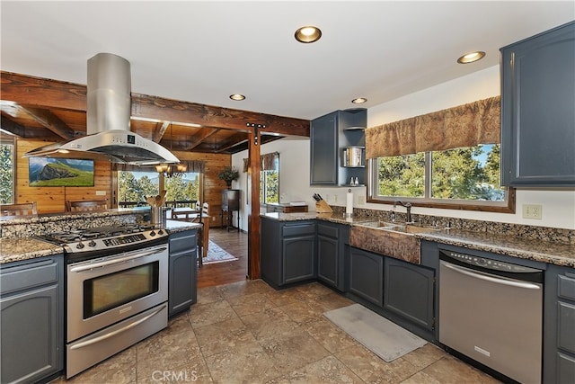 kitchen with appliances with stainless steel finishes, island range hood, wood walls, beamed ceiling, and sink