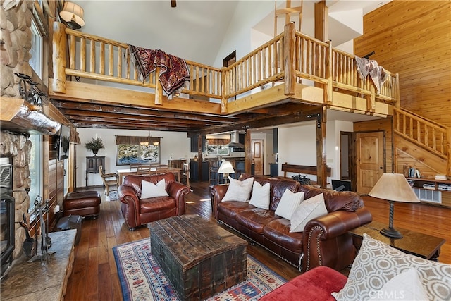 living room featuring dark hardwood / wood-style flooring, wooden walls, a chandelier, and a high ceiling