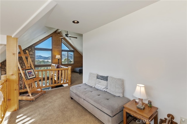 sitting room featuring lofted ceiling with beams, wooden walls, a mountain view, carpet floors, and ceiling fan