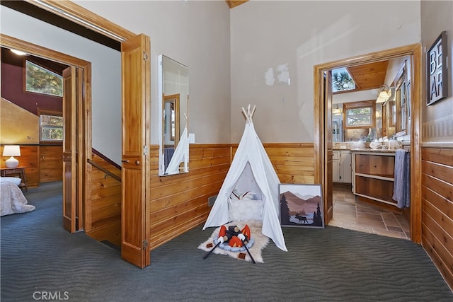 playroom with dark colored carpet and wooden walls