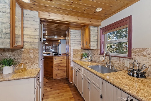 kitchen with sink, backsplash, wood ceiling, light stone countertops, and light wood-type flooring