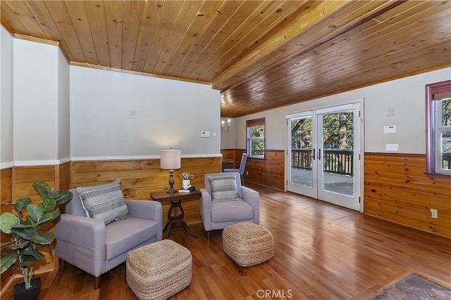 living area with wood walls, wood-type flooring, wooden ceiling, and french doors