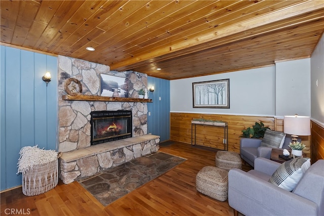 living room featuring a stone fireplace, hardwood / wood-style floors, wooden ceiling, and wooden walls