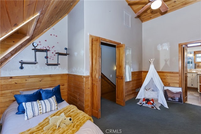 carpeted bedroom with lofted ceiling, wooden ceiling, ensuite bathroom, and wood walls