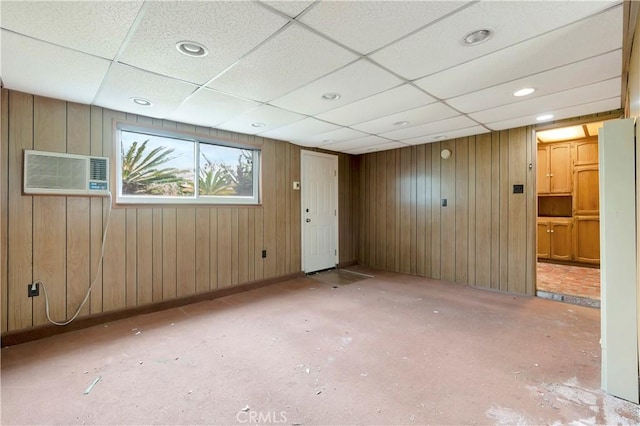 empty room with a drop ceiling and wood walls