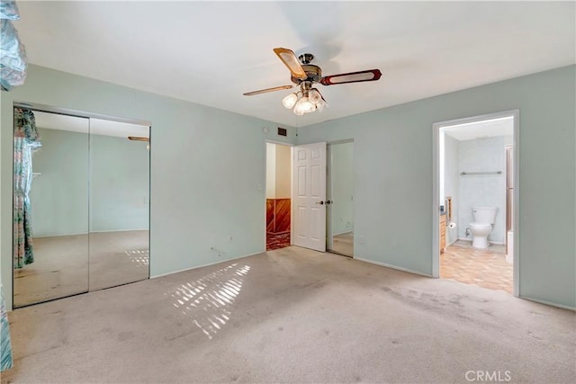 unfurnished bedroom with connected bathroom, light colored carpet, ceiling fan, and a closet