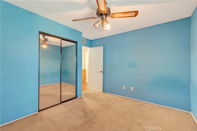 unfurnished bedroom featuring light colored carpet, a closet, and ceiling fan