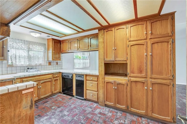 kitchen with sink, backsplash, tile counters, and dishwasher