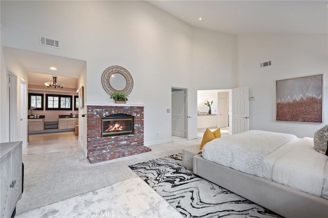 carpeted bedroom with ensuite bathroom, high vaulted ceiling, a fireplace, and a chandelier