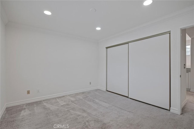 unfurnished bedroom featuring ornamental molding, light carpet, and a closet