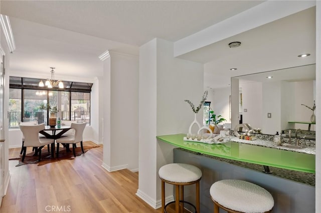 kitchen featuring sink, hanging light fixtures, light wood-type flooring, a notable chandelier, and dark stone counters