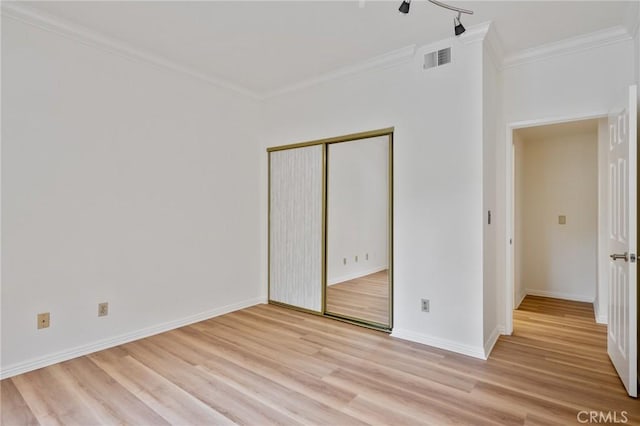 unfurnished bedroom featuring crown molding, light hardwood / wood-style floors, and a closet