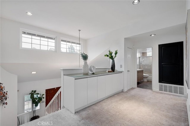 kitchen featuring hanging light fixtures, light colored carpet, and white cabinets