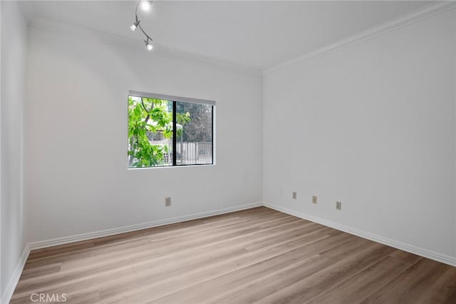 empty room with ornamental molding, track lighting, and light hardwood / wood-style floors