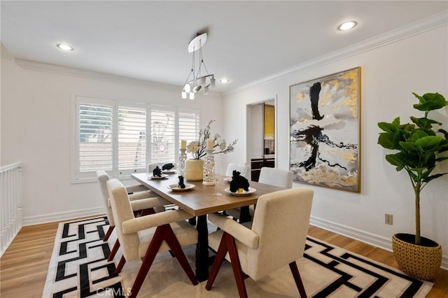 dining area with ornamental molding, a chandelier, and light hardwood / wood-style floors